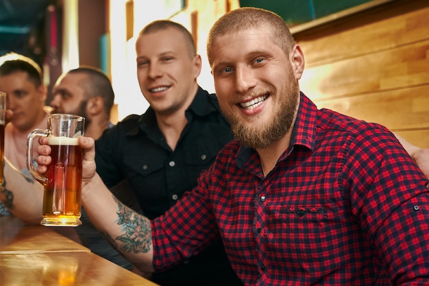 Gelukkig mannelijke hipster met tatoeage glas bier houden