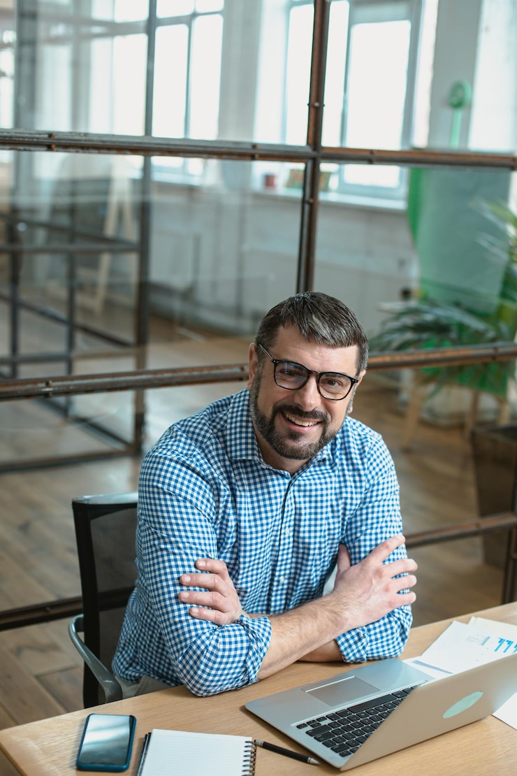 Gelukkig mannelijke ondernemer bezig met laptop aan tafel in modern kantoor
