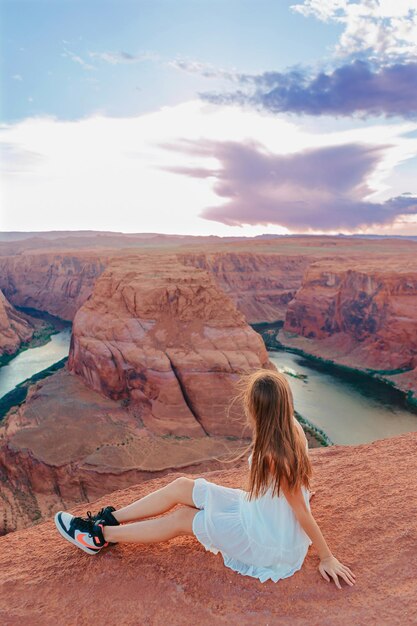 Gelukkig meisje aan de rand van de klif bij Horseshoe Band Canyon in Page Arizona Avontuur en toerisme concept Mooie natuur in de VS