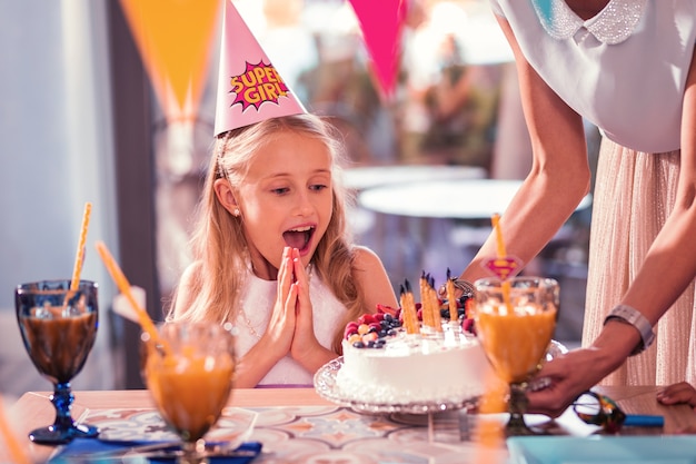 Gelukkig meisje applaudisseren en tijdens het zien van haar verjaardagstaart