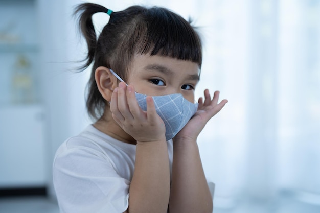 Gelukkig meisje dat een gezichtsmasker draagt Meisje dat een masker draagt om een pandemie van het coronavirus te voorkomen