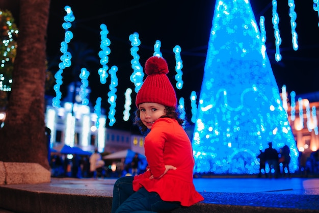 Gelukkig meisje dat Kerstmis viert met lichten en kerstelementen