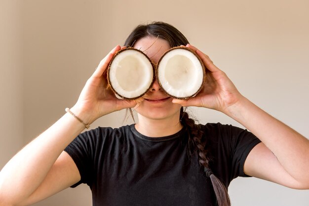 Gelukkig meisje dat kokosnoot voor haar ogen houdt