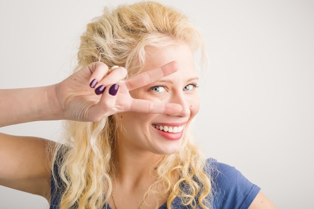 Gelukkig meisje dat twee vingers voor haar gezicht houdt