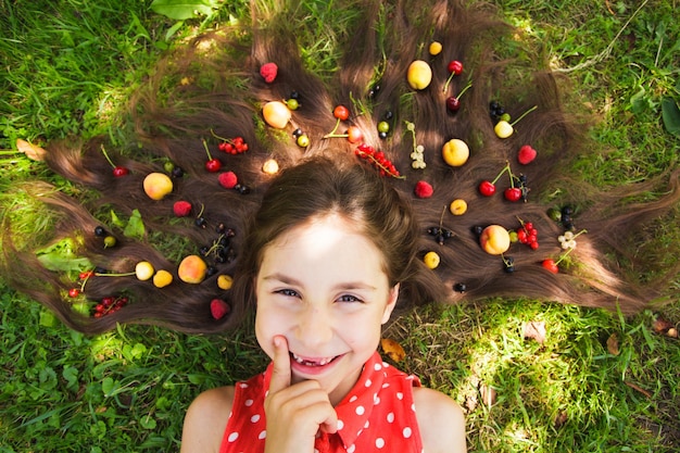 Gelukkig meisje denkt aan gezond eten. Vers fruit op haar haar. Fruitarisme en raw foodism concept