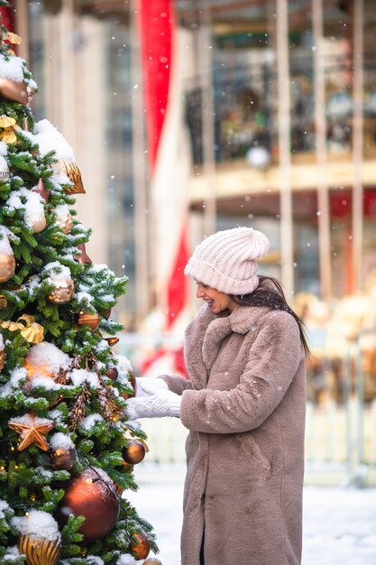 Gelukkig meisje dichtbij sparrentak in sneeuw voor nieuw jaar.