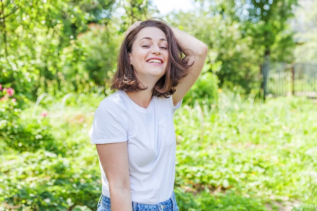Gelukkig meisje die openlucht mooie jonge brunete vrouw glimlachen die op groen park of tuin rusten