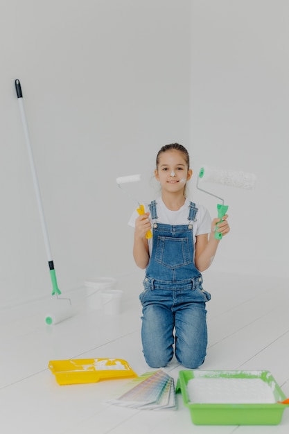 Gelukkig meisje in denim overall staat op knieën