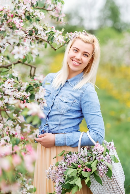 Gelukkig meisje in een bloeiende tuin. blonde jonge vrouw in in het voorjaar bloeiende tuin,