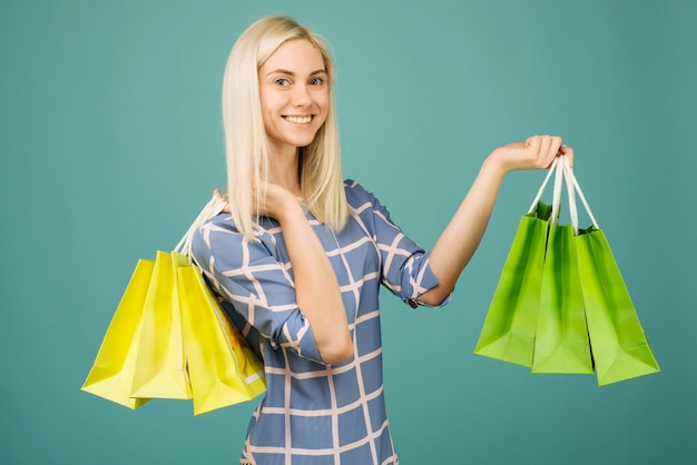 Gelukkig meisje in een geruite blouse houdt boodschappentassen op blauw