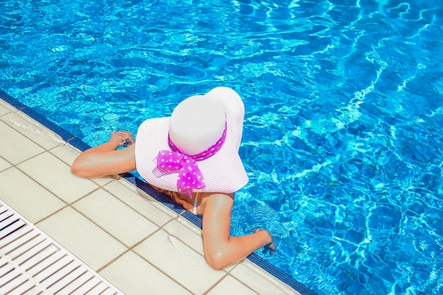Gelukkig meisje in een hoed bij het zwembad over de aard van de kust
