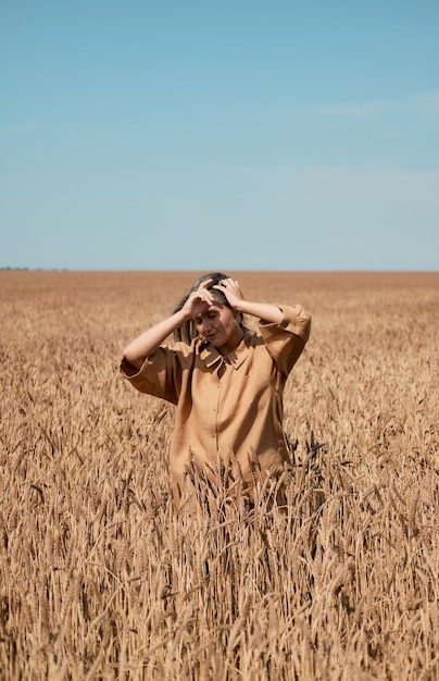 Foto gelukkig meisje in een hoed die danst in een veld op een heldere blauwe hemelachtergrond