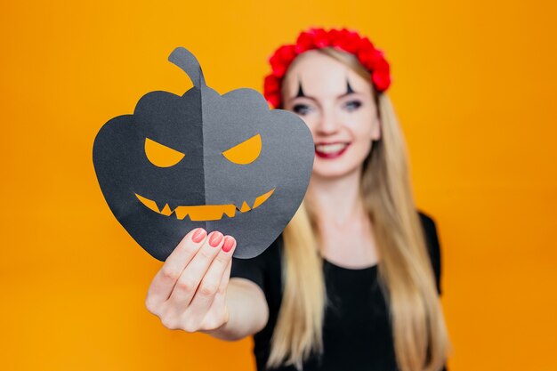 Gelukkig meisje in halloween kostuum met pompoen en geïsoleerd op oranje