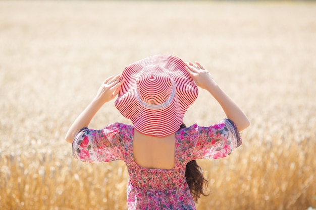 Gelukkig meisje in hoed op tarweveld. Grote hoed en lang haar waait