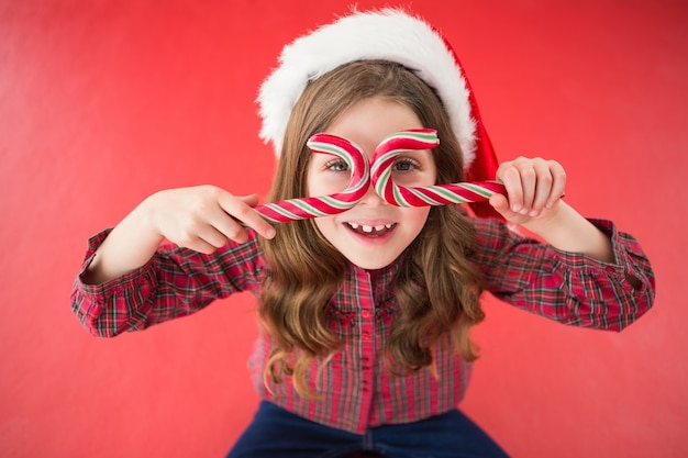 Gelukkig meisje in kerstmuts bedrijf snoep stokken