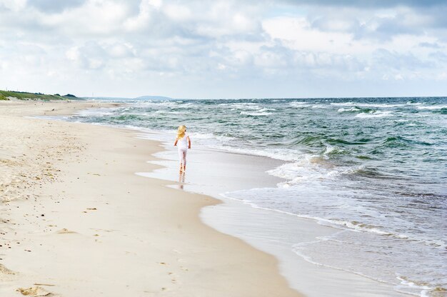 Gelukkig meisje in kleren op het strand van de Baltische Zee aan het Koerse land in Litouwen.