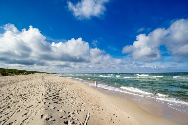 Gelukkig meisje in kleren op het strand van de Baltische Zee aan het Koerse land in Litouwen.