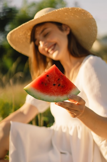 Gelukkig meisje in openluchtpark met verfrissende watermeloen fruitvrouw eet een stuk watermeloen