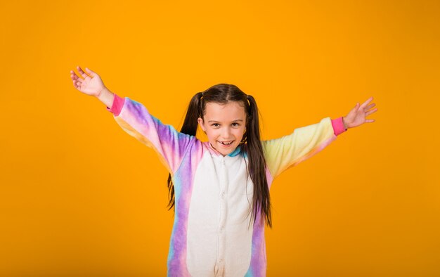 Gelukkig meisje in pluche pyjama geniet op een gele achtergrond met een plek voor tekst