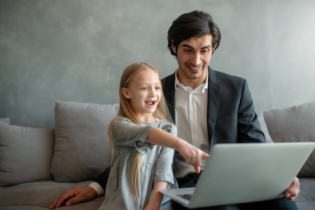 Gelukkig meisje kijken naar een film op de computer met haar vader