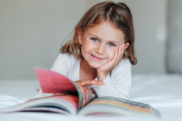 Gelukkig meisje kind ligt op bed lees het boek Comfort gezellig huis concept Onderwijs ontwikkelen kind peuter