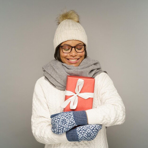 Gelukkig meisje knuffel kerstcadeau met warme trui sjaal muts en handschoenen wintervakantie en verkoop