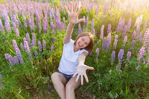 Gelukkig meisje lachend buiten. mooie jonge brunette vrouw rusten op zomer veld met bloeiende wilde bloemen. gratis gelukkige europese vrouw. positieve menselijke emotie gezichtsuitdrukking.