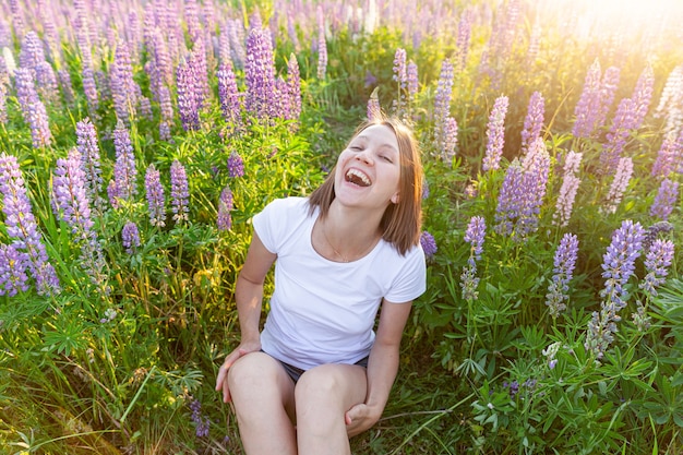 Gelukkig meisje lachend buiten. Mooie jonge brunette vrouw rusten op zomer veld met bloeiende wilde bloemen groene tafel. Gratis gelukkige Europese vrouw. Positieve menselijke emotie gezichtsuitdrukking.