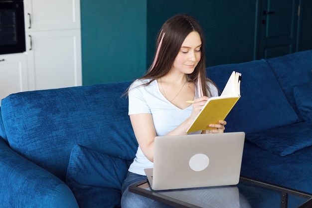 Gelukkig meisje leert online op afstand met behulp van laptop vanuit huis