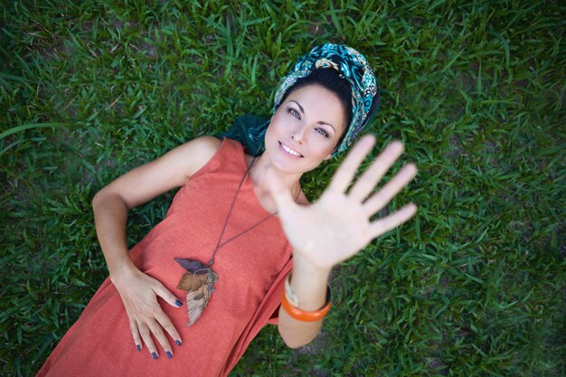 gelukkig meisje ligt op gras en steekt haar hand uit