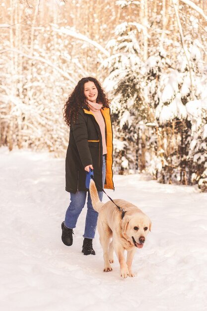 Gelukkig meisje loopt met hond labrodor in winter park