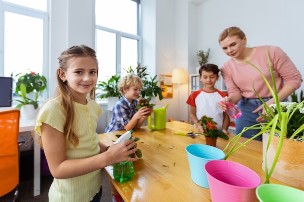 Gelukkig meisje. Meisje met donkere ogen voelt zich gelukkig nadat ze planten water heeft gegeven met klasgenoten en leraar bij de les ecologie