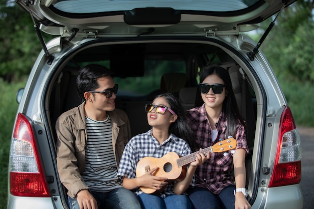 Gelukkig meisje met Aziatische familie zitten in de auto
