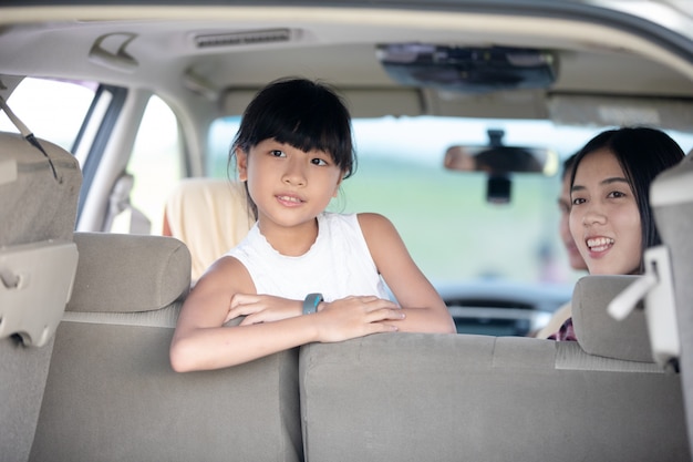 Gelukkig meisje met aziatische familie zitten in de auto