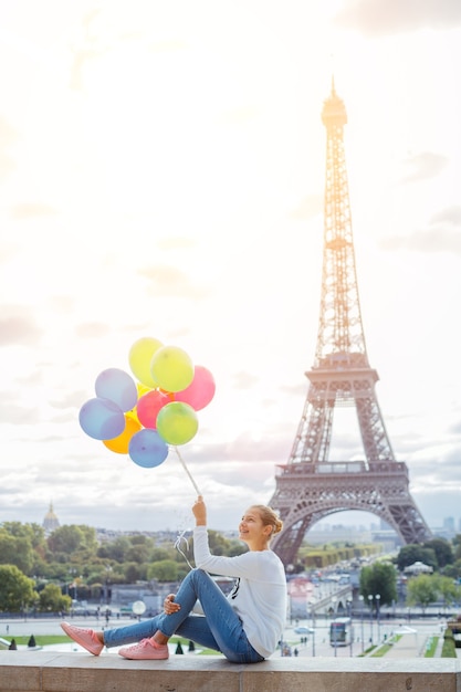 Gelukkig meisje met bos van kleurrijke ballonnen in Parijs in de buurt van de Eiffeltoren.