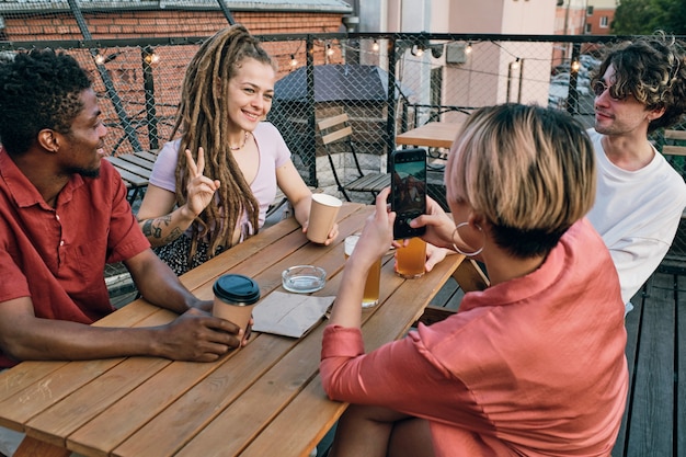 Gelukkig meisje met drankje poseren voor een van haar vrienden