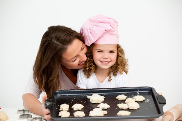 Gelukkig meisje met haar moeder die een plaat met koekjes toont