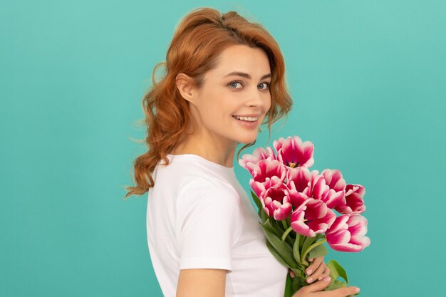 Gelukkig meisje met het boeket van de tulpenbloem op de dag van blauwe achtergrondvrouwen