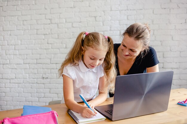 Gelukkig meisje met moeder die thuis online studeert. Online leren of onderwijstechnologie concept