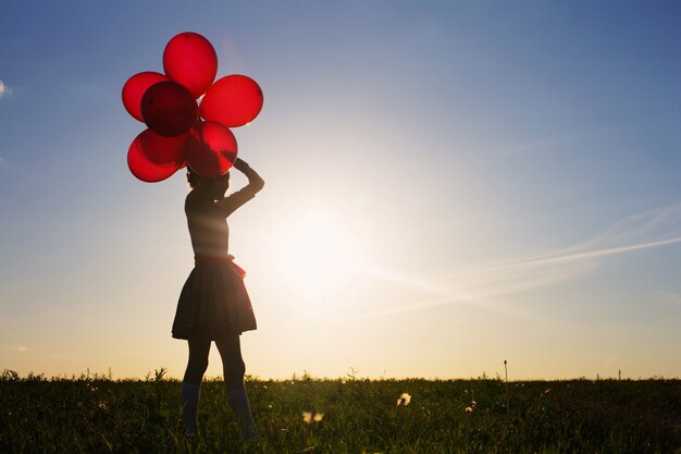 Gelukkig meisje met rode ballonnen buiten