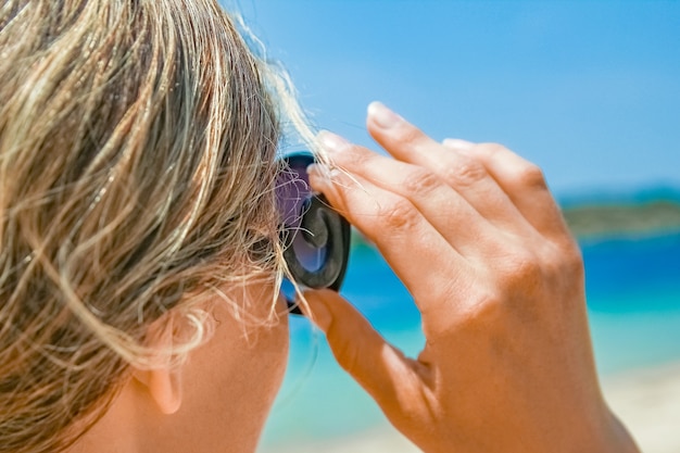 Gelukkig meisje met zonnebril aan zee op aard