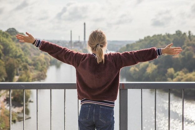 Foto gelukkig meisje op de brug en vrij voelen en kijken naar de blauwe rivier