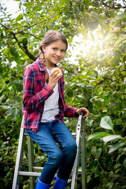 Gelukkig meisje rijpe appels plukken in de tuin op zonnige dag