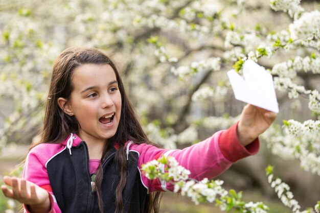 Foto gelukkig meisje spelen met speelgoed vliegtuig in de tuin