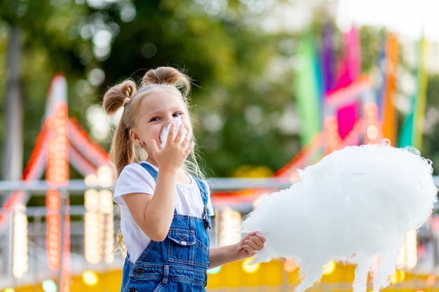 Gelukkig meisje suikerspin eten in pretpark