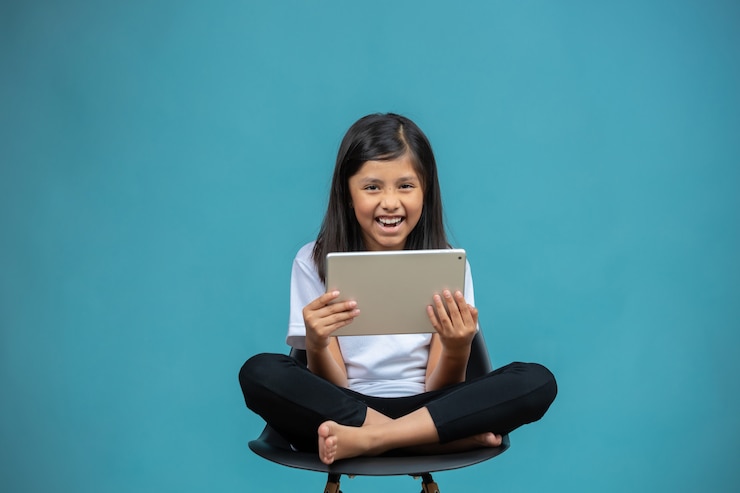 gelukkig meisje zittend op een stoel kijken naar tablet