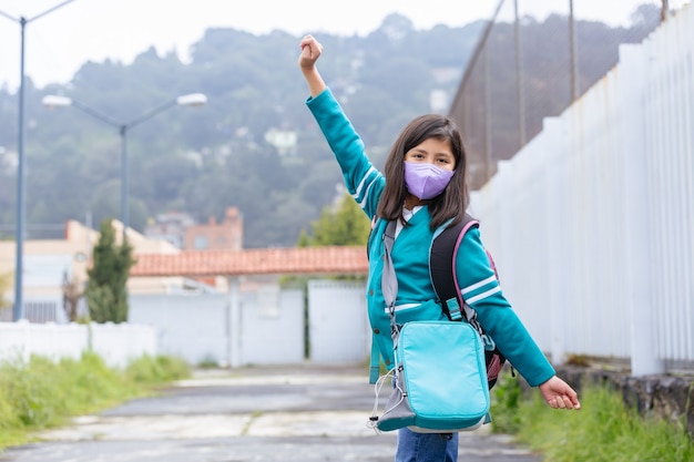 Gelukkig Mexicaans meisje opgewonden terug naar school met beschermend gezichtsmasker na coronavirusvergrendeling