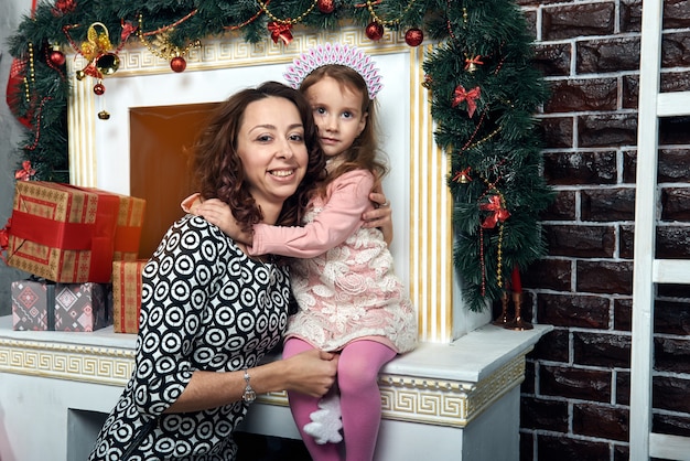 Gelukkig moeder en dochter bij de open haard voor wintervakantie. Kerstavond en oudejaarsavond.