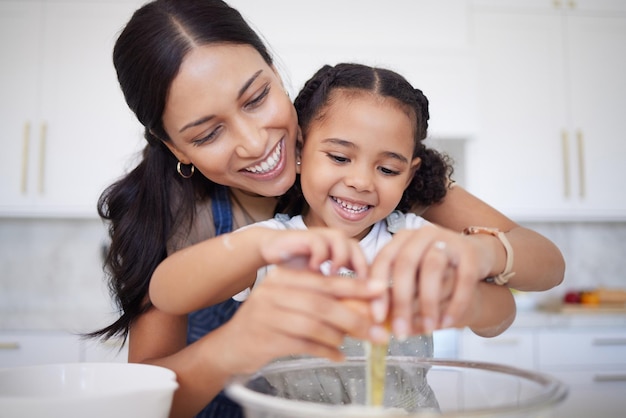 Gelukkig moeder en dochter bonding bakken in een keuken thuis Lachende alleenstaande moeder leraar haar dochtertje huishoudelijke vaardigheden tegen heldere kopie ruimte Kid helpt haar moeder een maaltijd te bereiden