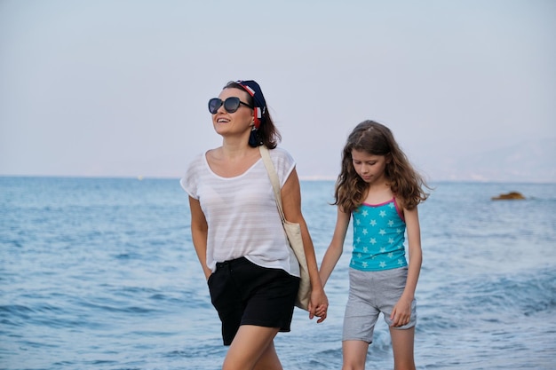 Gelukkig moeder en dochter kind lopen samen op het strand hand in hand